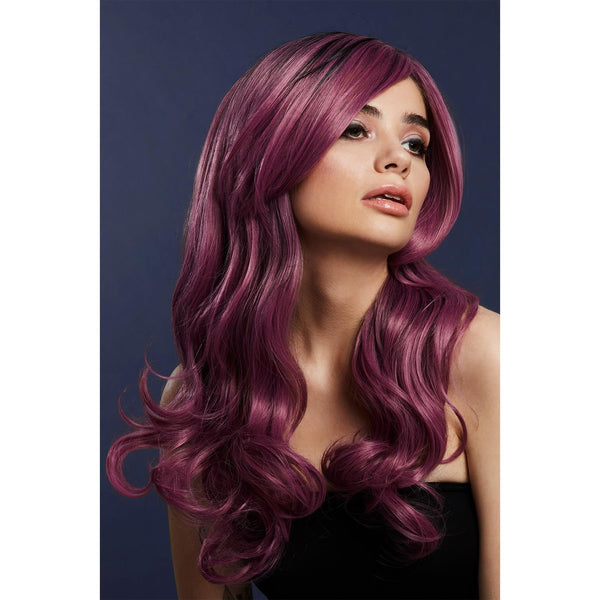 Woman with long, wavy a purple wig against a dark background