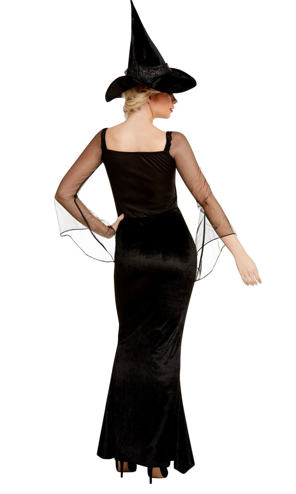 Back view of a woman wearing a black witch costume with a long dress and hat on a white background