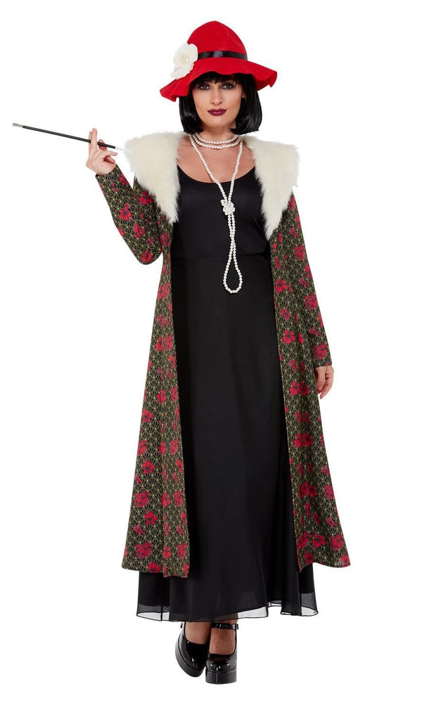 Woman in a 1920s Peaky Blinders costume with a long coat, black dress, red hat, and holding a cigarette on a white background