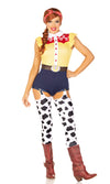 A woman modeling a Woody-inspired costume. The costume includes a yellow gingham top with red trim and white buttons, navy shorts, black-and-white cow-print leg warmers, and brown boots.