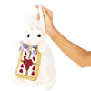 A white plush rabbit purse with long ears, black eyes, and a blue ribbon bow, wearing a cream bib with red hearts and gold trim. A hand is holding the rabbit.