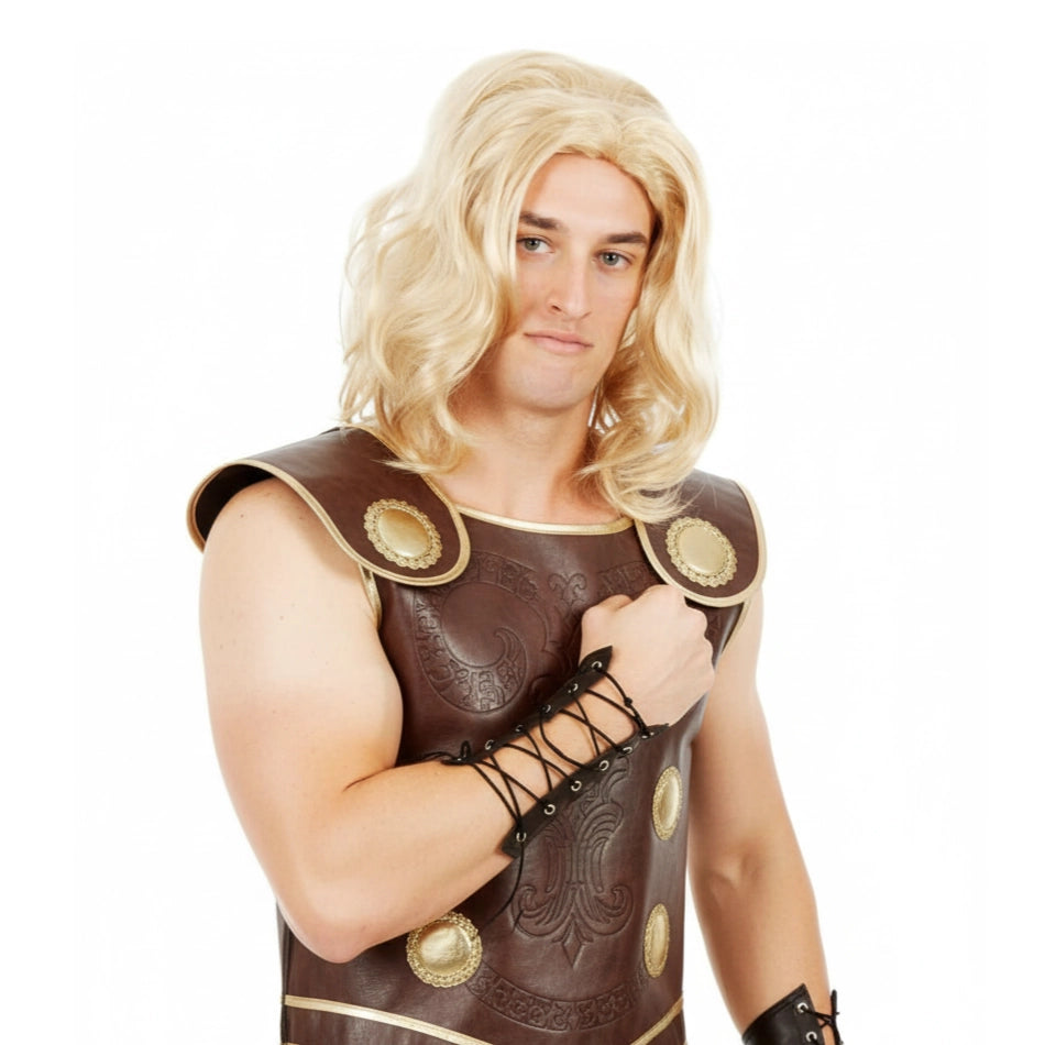 A man wearing a brown leather-look gladiator-style costume top with gold-tone circular accents, black lace-up arm details, and a blonde wig.