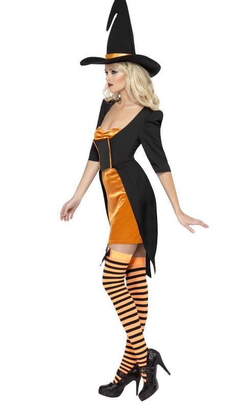 Side of a female model wearing an orange and black witch costume with a black hat, holding a broom. The costume includes a jacket dress and hat.